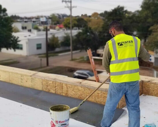 Roofer installing parapet flashing on commercial roofing project.