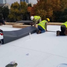 Our roofers laying down TPO single ply membrane over insulation for a new commercial flat roof project in Downtown OKC